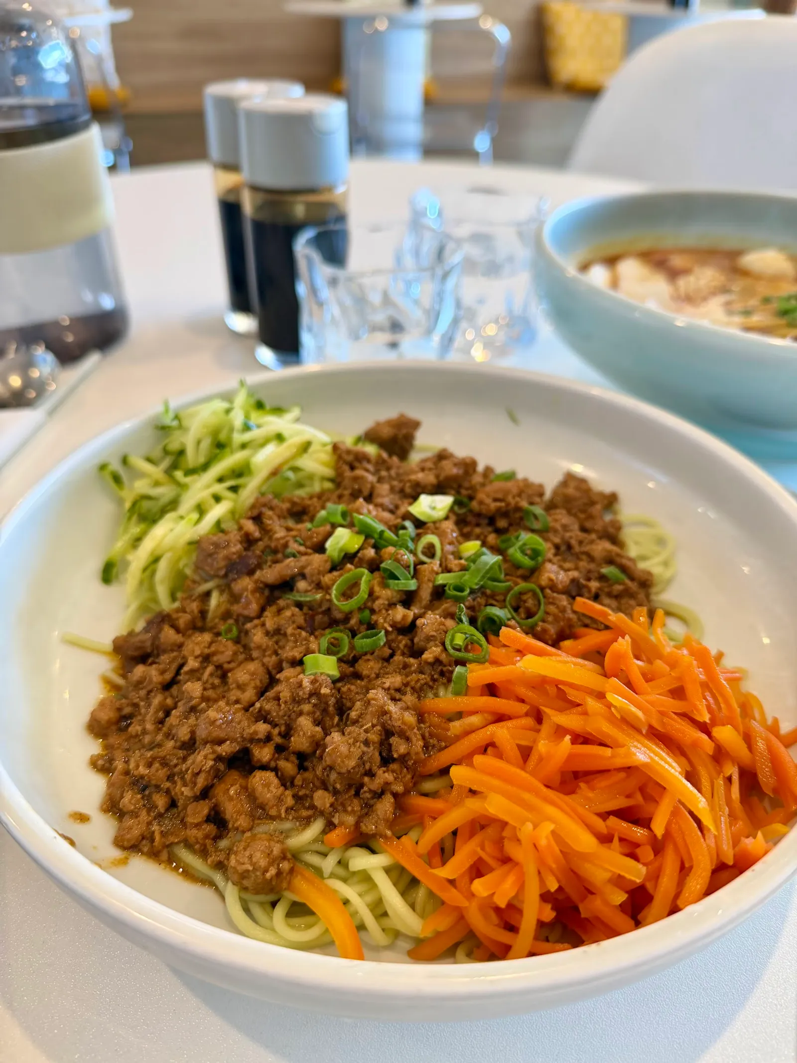 Bowl of Peking zha-jiang noodles with green cucumber, orange carrot and spiced minced pork