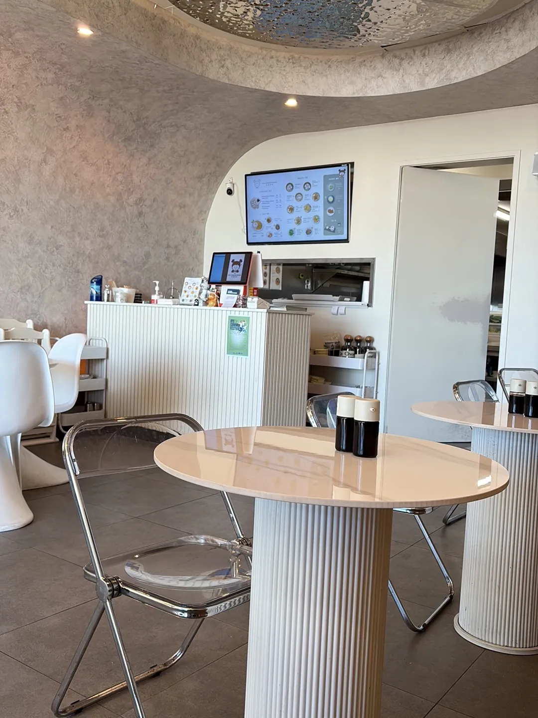 Modern dining room interior with white pedestal tables, acrylic chairs, and silver domed ceiling