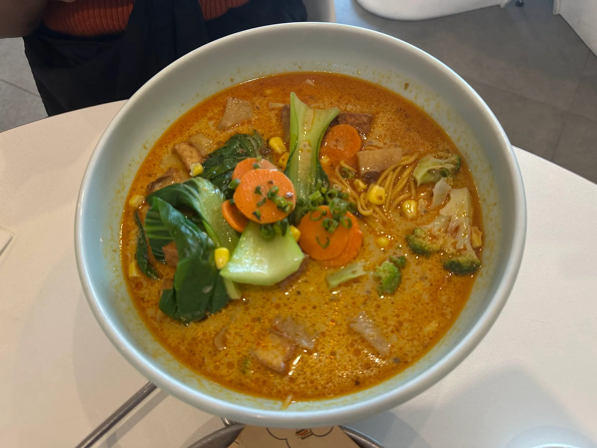Overhead view of vegetable curry ramen with colourful vegetables, bok choy and golden broth