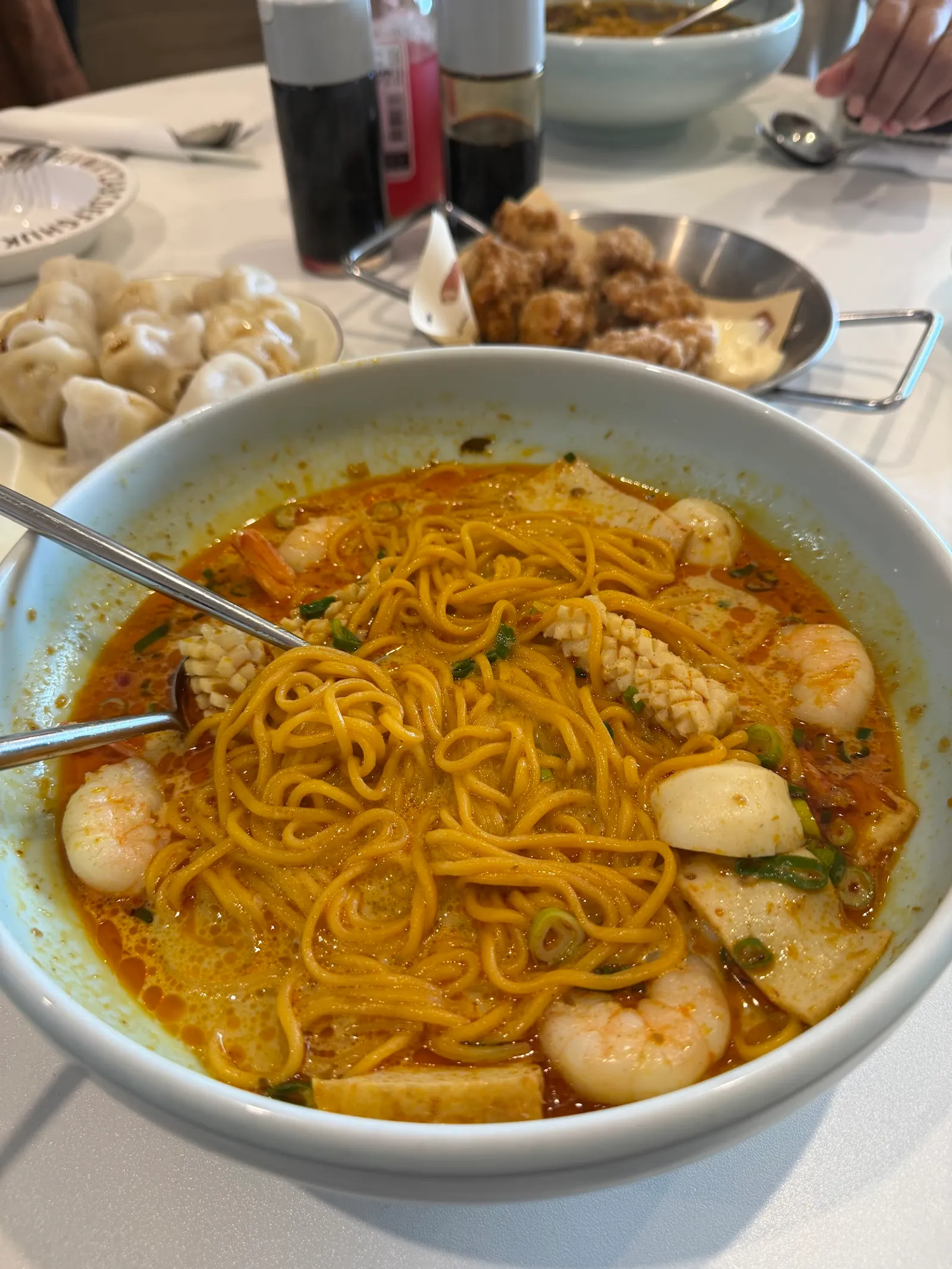 Bowl of tomyum seafood noodle soup with prawns, calamari, fish balls in orange broth