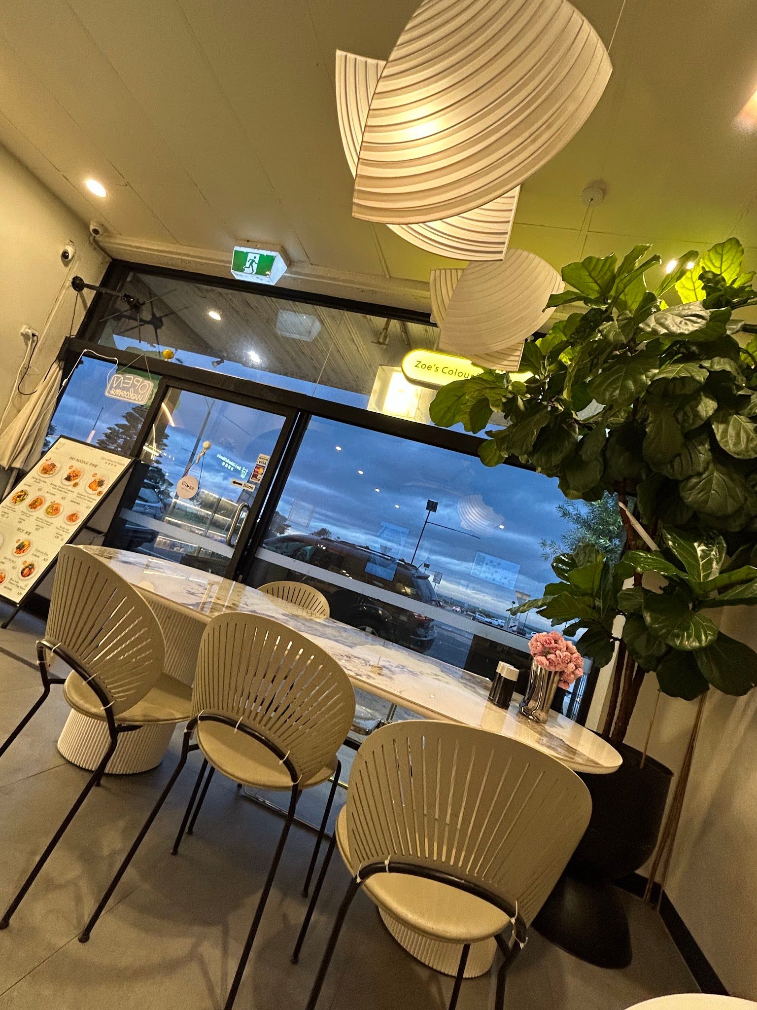 Evening dining room interior with rattan chairs, marble table, paper lanterns and fiddle-leaf fig