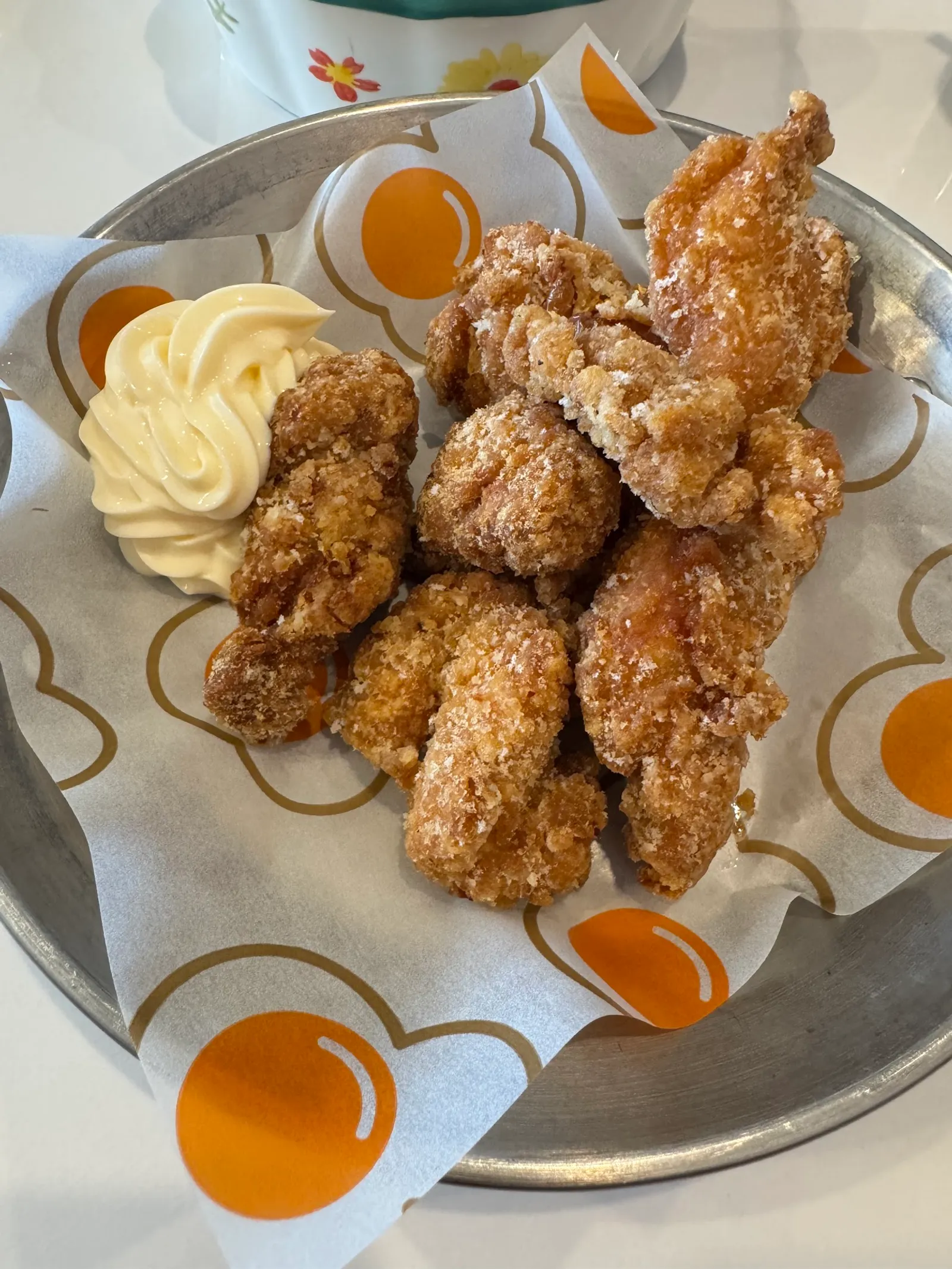 Fried karaage chicken wings on metal tray with retro-pattern paper and aioli dipping sauce